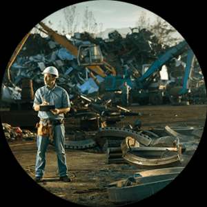 Man standing next to scrap metal heap